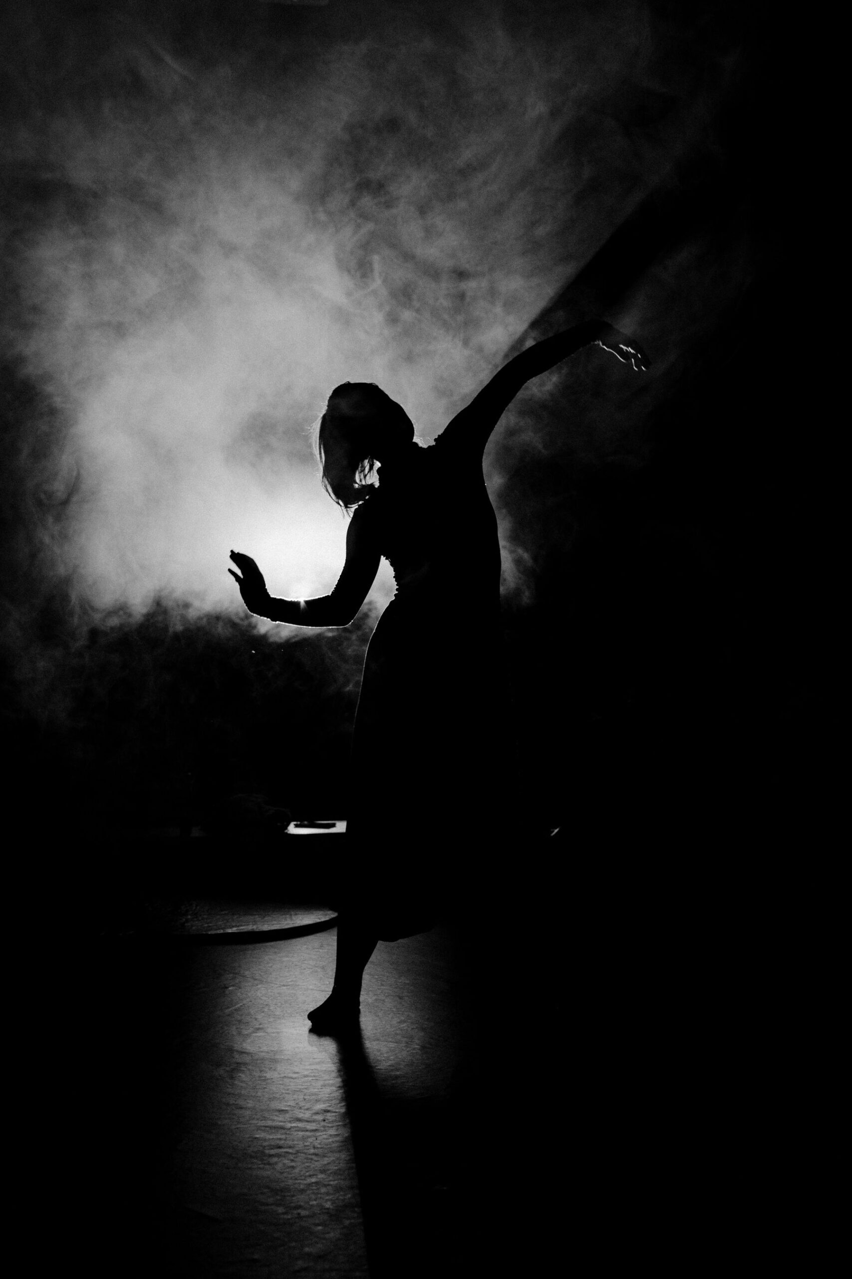 A dancer in silhouette on a smoke-lit stage